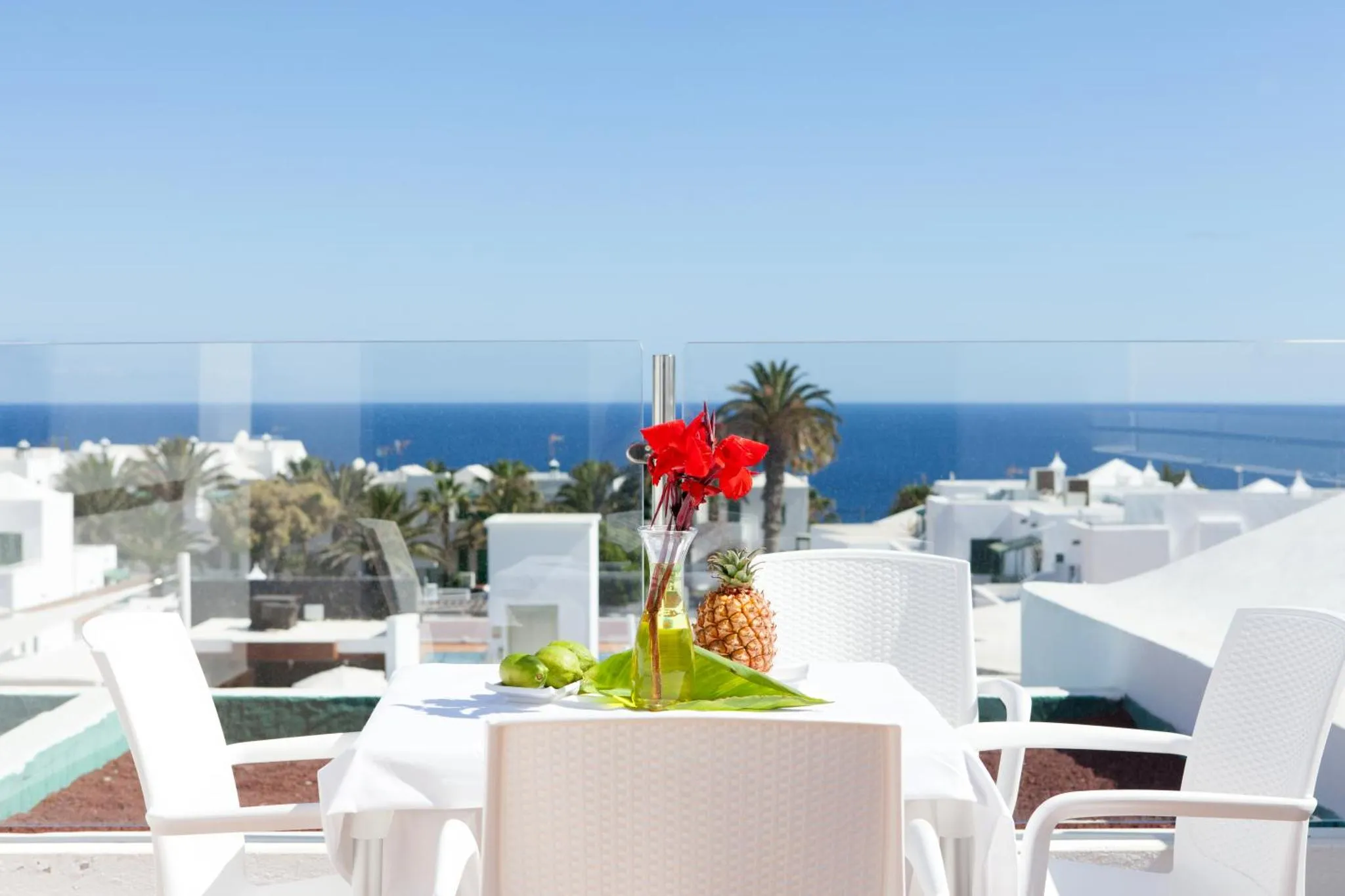 Table blanche avec des fruits frais sur une terrasse ensoleillée avec vue sur la mer.