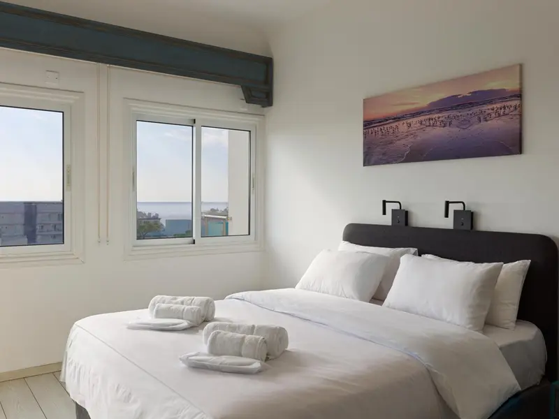 Une chambre lumineuse avec un grand lit et une vue sur la mer.
