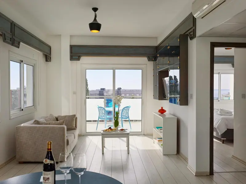 Espace de vie lumineux avec canapé et vue sur une piscine.