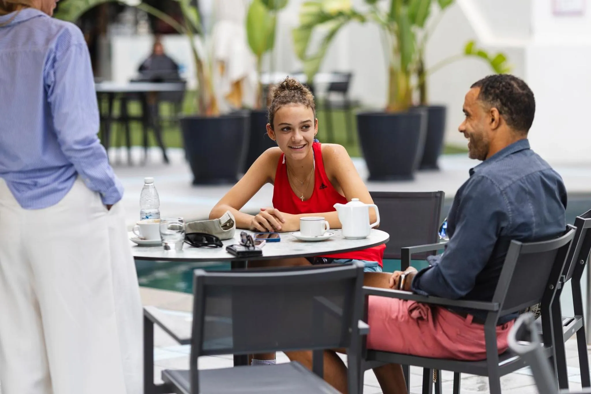Des personnes sont assises à une table en extérieur, profitant de boissons et de conversations.