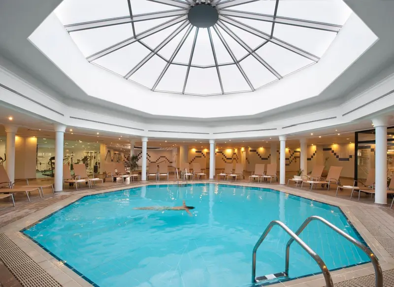 Une piscine intérieure lumineuse sous une verrière octogonale.