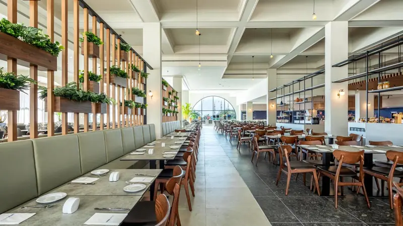 Une grande salle lumineuse avec de longues tables dressées pour un repas.