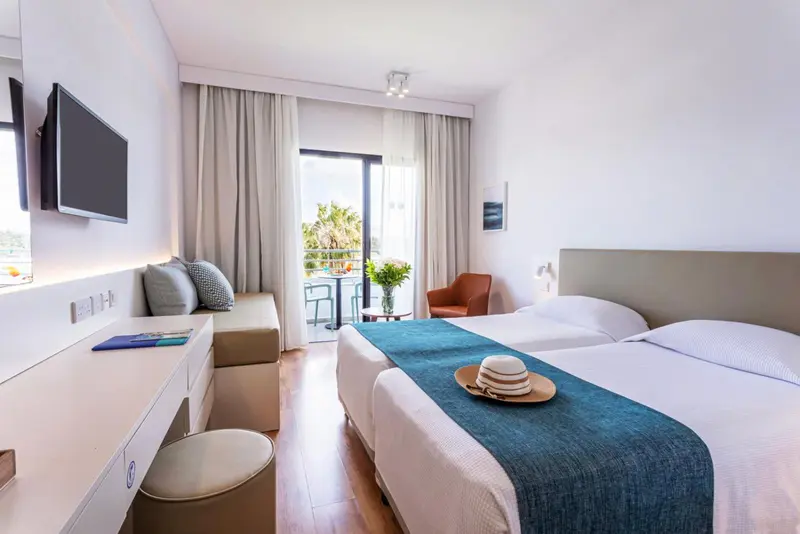 Une chambre lumineuse avec un lit double et un coin salon.