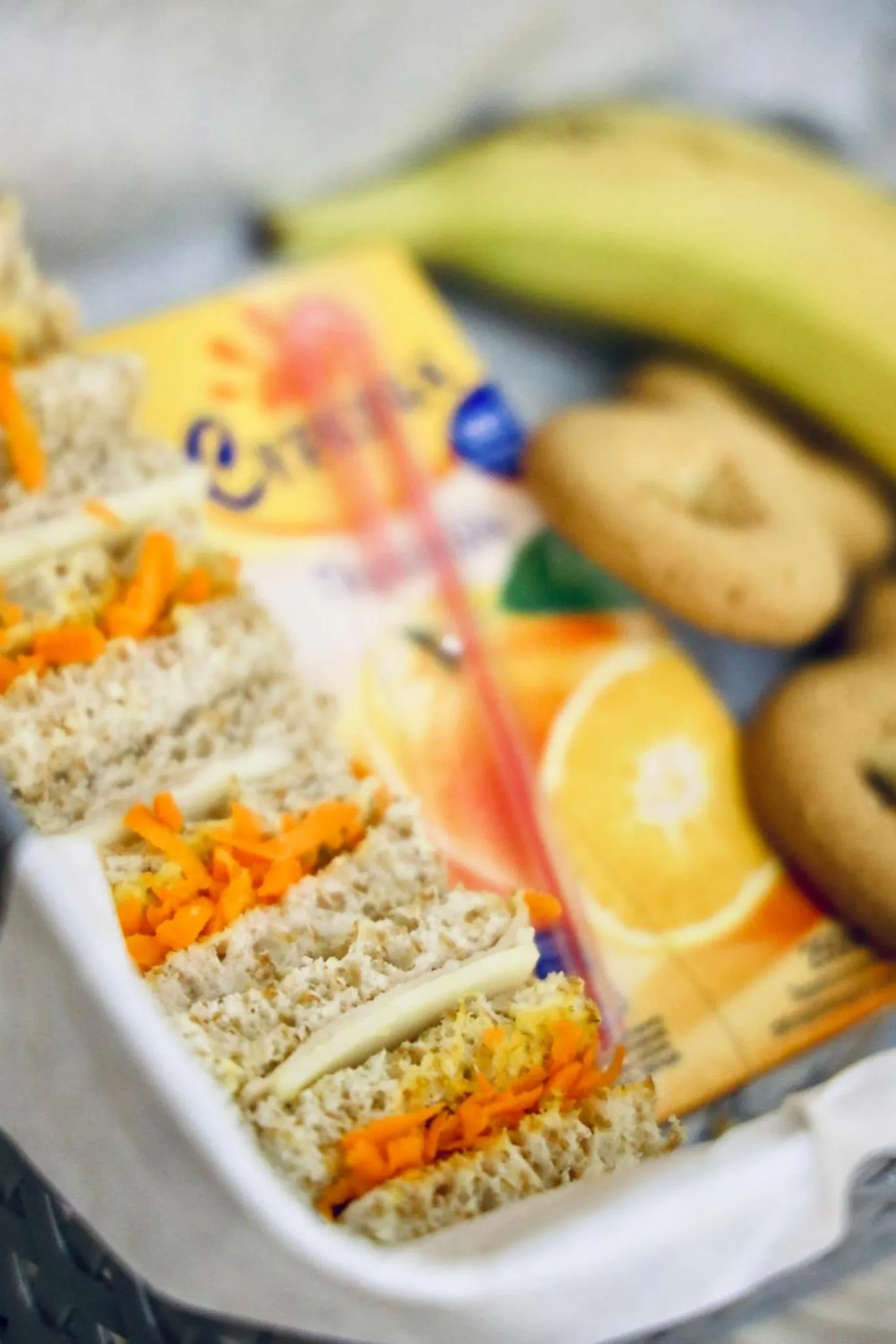 Assortiment de sandwichs, de jus de fruits et de biscuits présentés dans un récipient.