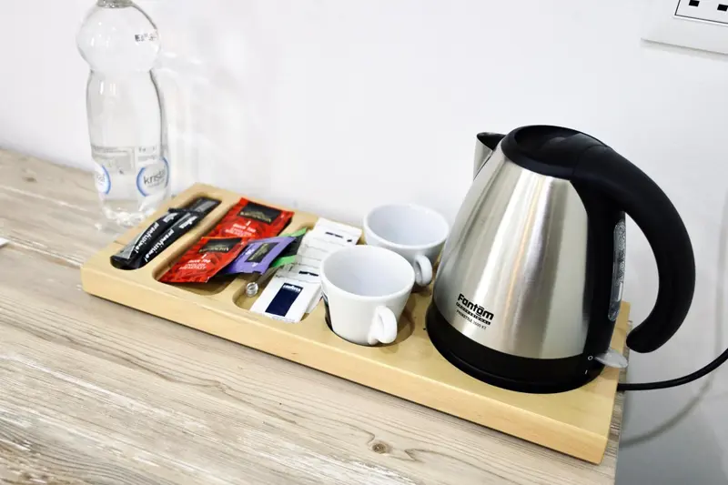 Une bouilloire et des sachets de thé sont posés sur un plateau en bois.