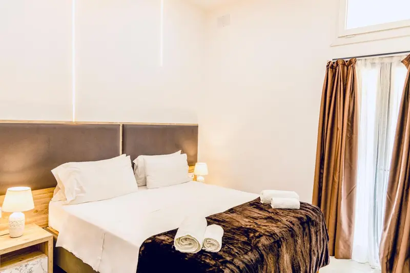 Une chambre lumineuse avec un grand lit recouvert de draps blancs et de couvertures.