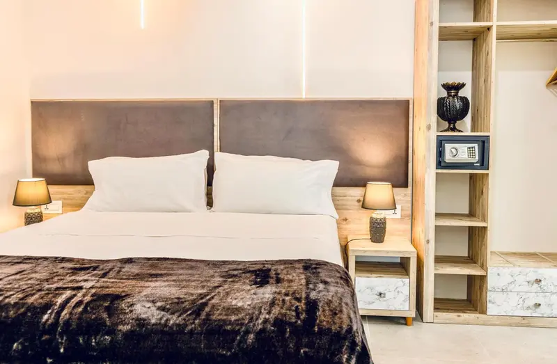 Une chambre avec un grand lit recouvert d'une couverture sombre et de coussins blancs.