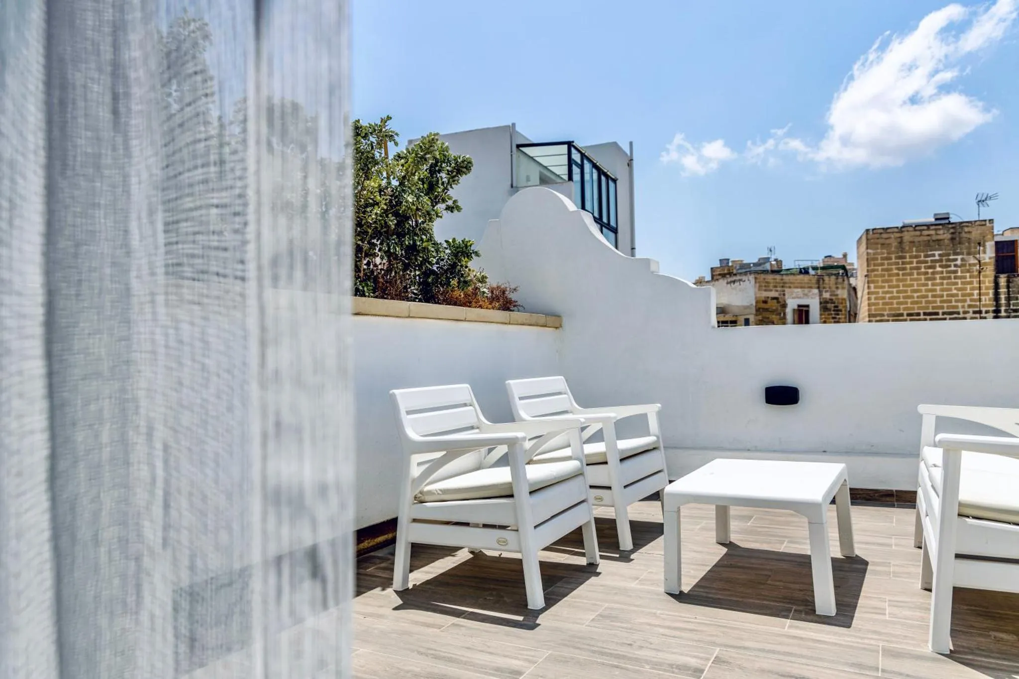 Terrasse aménagée avec mobilier blanc et vue sur un paysage urbain.
