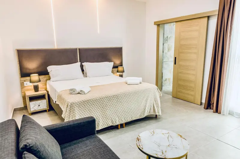 Une chambre lumineuse avec un grand lit et un coin salon.