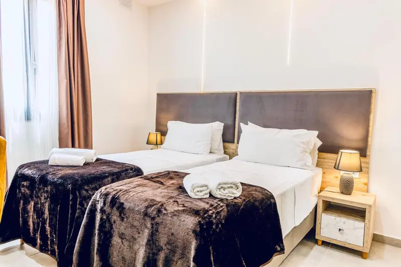 Une chambre avec deux lits simples et des couvertures foncées.