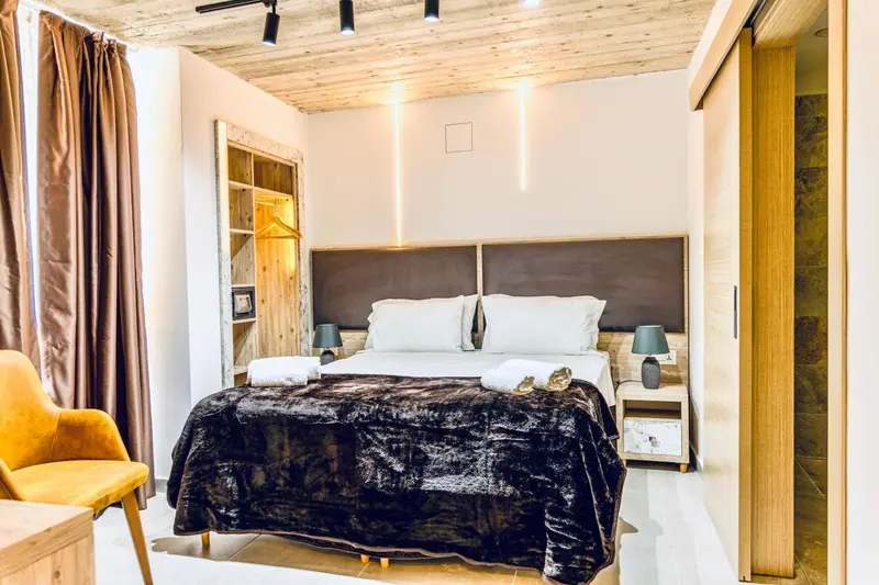 Une chambre à coucher lumineuse avec un grand lit recouvert d'une couverture sombre.