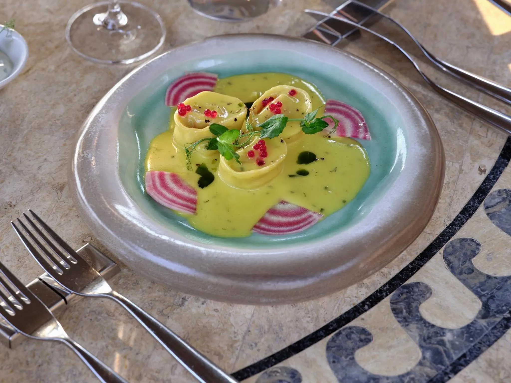 Assiette de pâtes fraîches décorée de légumes et d'herbes aromatiques.