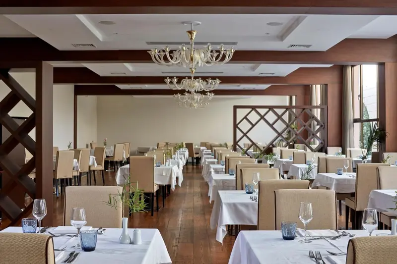 Une salle lumineuse est aménagée avec des tables dressées pour un repas.