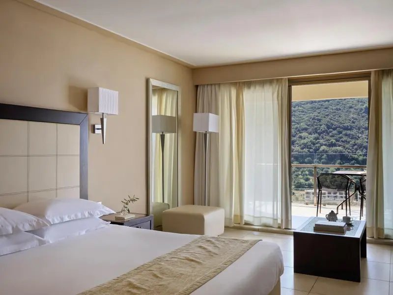 Chambre lumineuse avec un grand lit et une vue sur la nature.