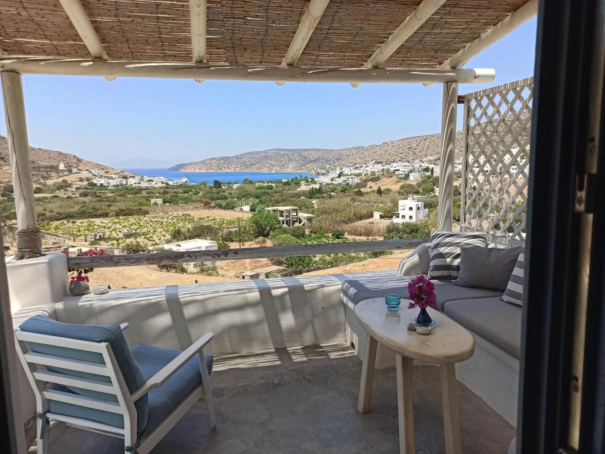 Terrasse ombragée avec mobilier d'extérieur donnant sur un paysage côtier.