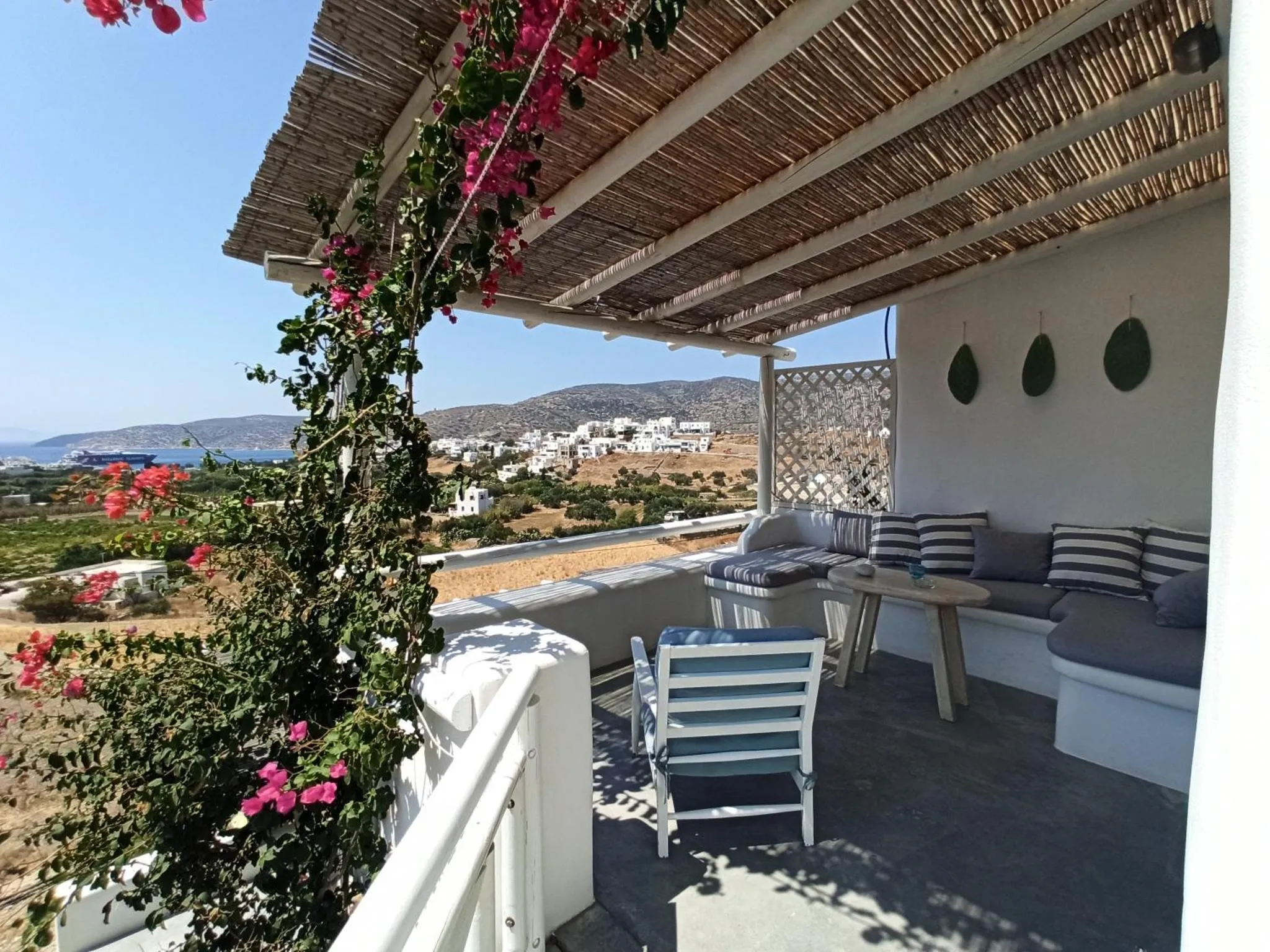 Terrasse ombragée avec mobilier d'extérieur et vue sur la mer.