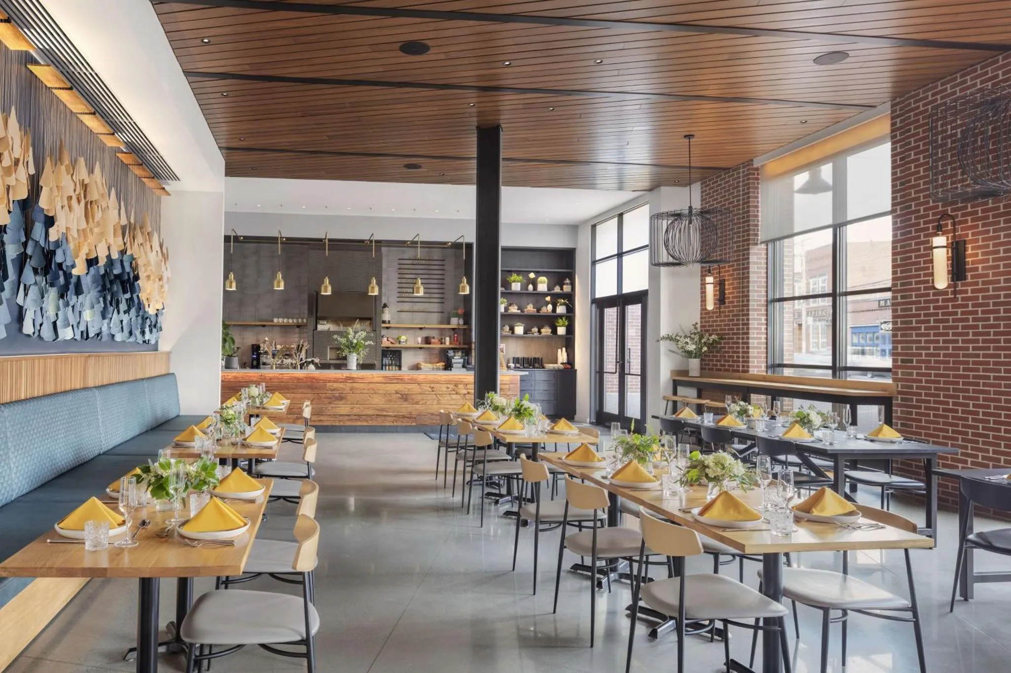 Une salle de restaurant lumineuse avec des tables dressées et une décoration murale abstraite.