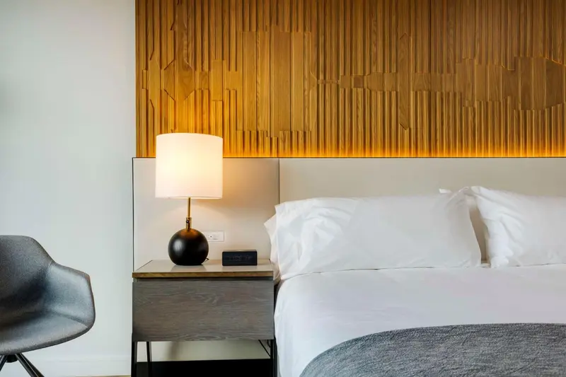 Une chambre lumineuse avec un lit blanc et une décoration murale en bois.