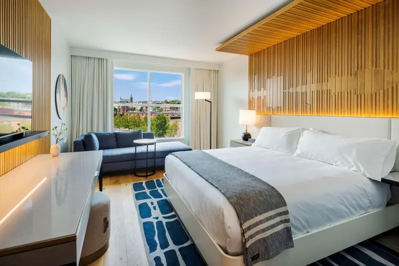 Une chambre lumineuse avec un grand lit et un canapé près d'une fenêtre.