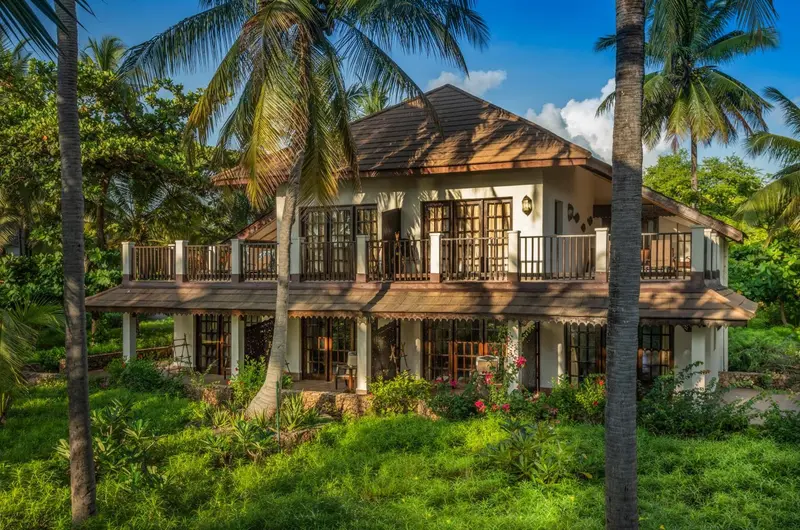 Bâtiment à deux étages avec des balcons en bois et une végétation luxuriante.
