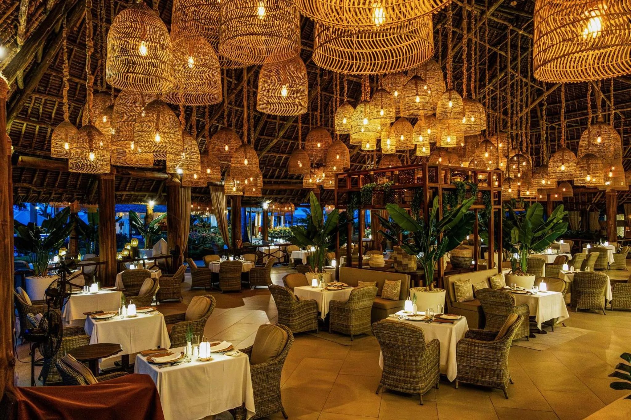 Une salle de restaurant illuminée par de nombreuses lampes en osier.