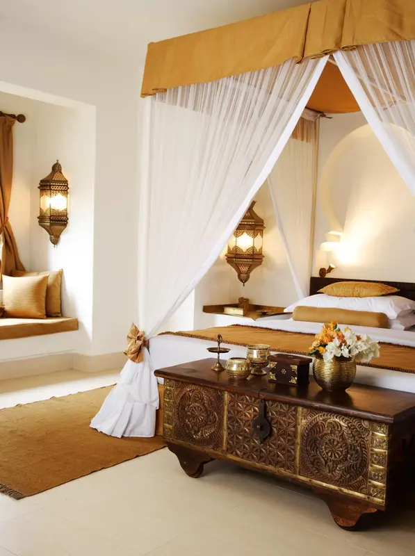 Une chambre lumineuse avec un grand lit à baldaquin et une décoration orientale.