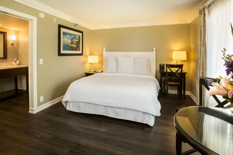 Une chambre lumineuse avec un grand lit recouvert d'une couette blanche et des tables de chevet.