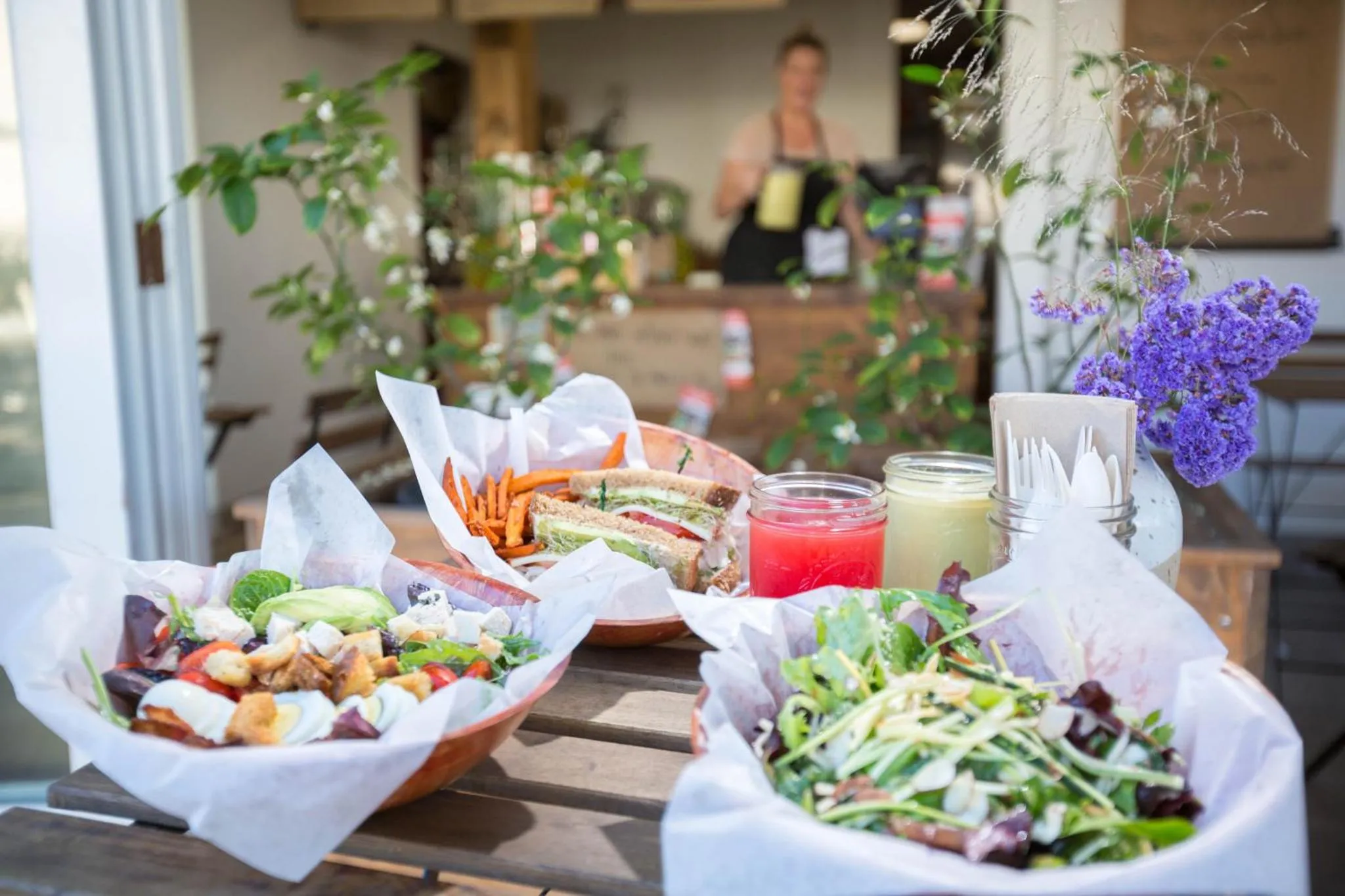 Assiettes de salades et sandwichs servis sur une table en bois.