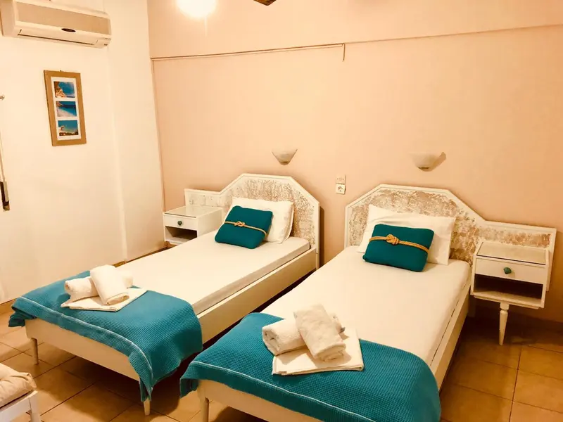 Deux lits simples avec couvertures turquoise dans une chambre lumineuse.