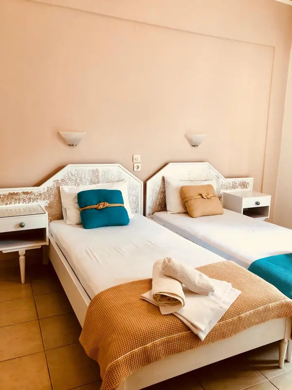 Deux lits simples décorés de coussins colorés dans une chambre lumineuse.