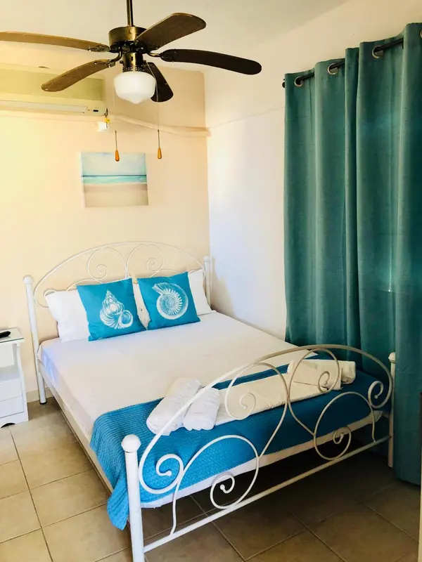 Une chambre lumineuse avec un lit recouvert d'une courtepointe bleue et de coussins décoratifs.
