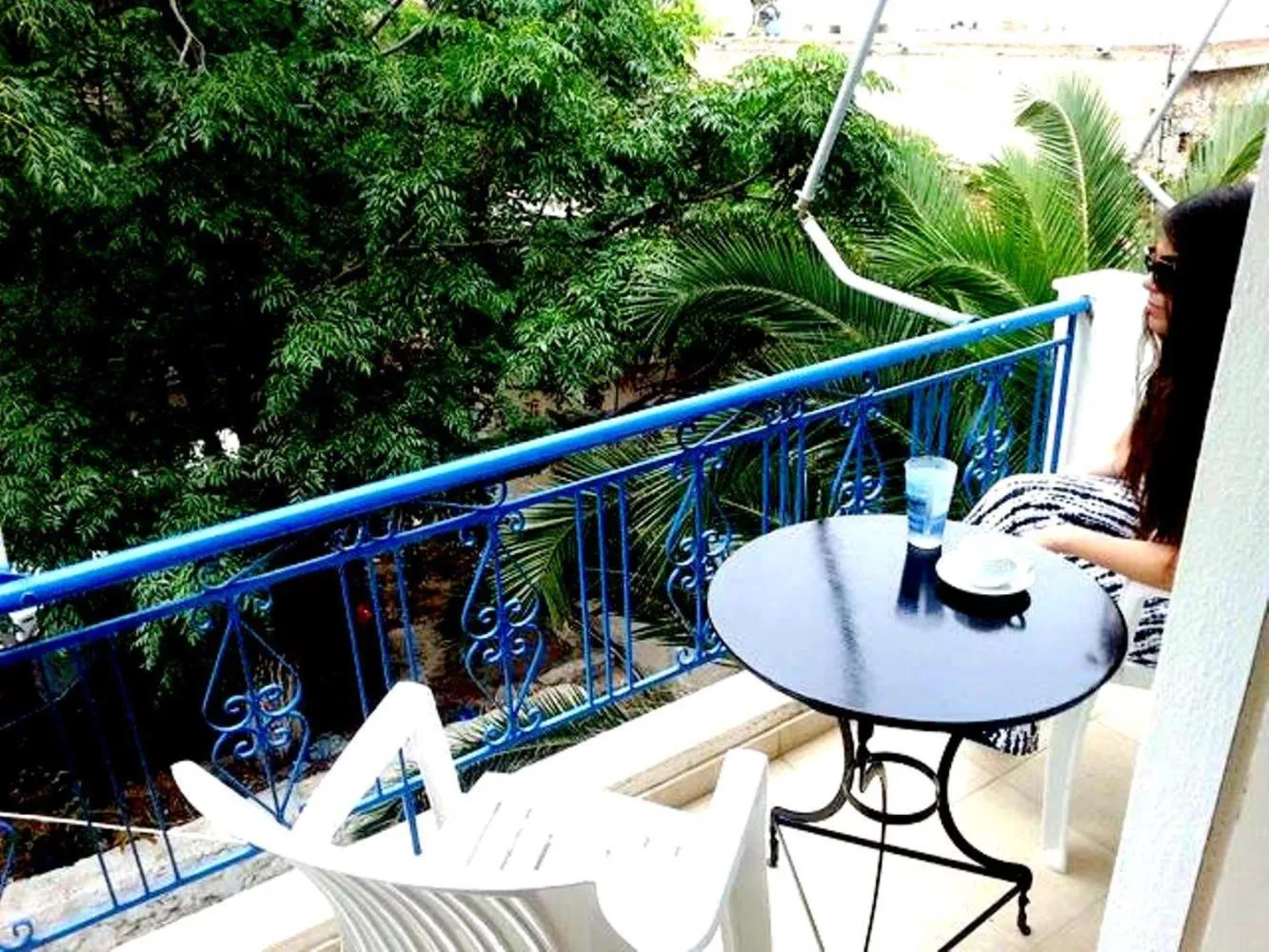 Une personne est assise à une table sur une terrasse ensoleillée.