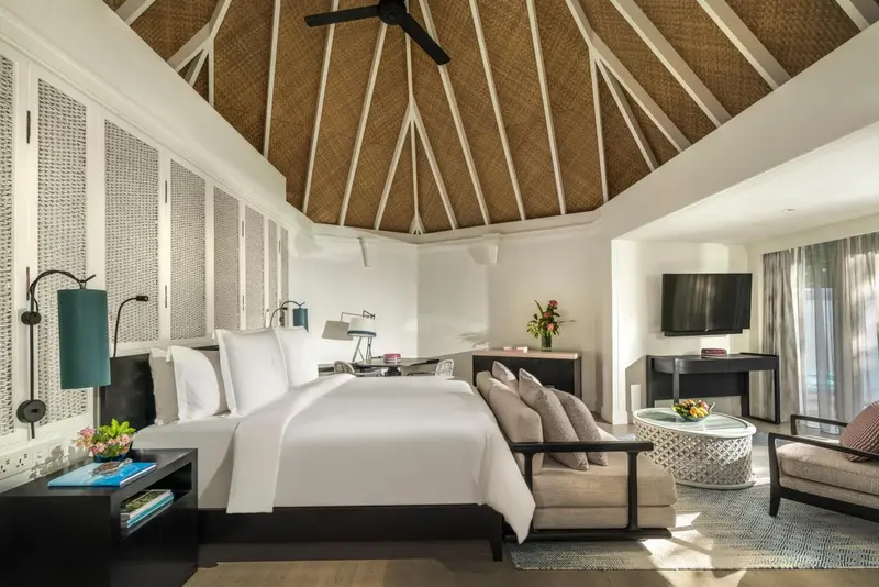 Une chambre lumineuse avec un lit king-size et un coin salon.