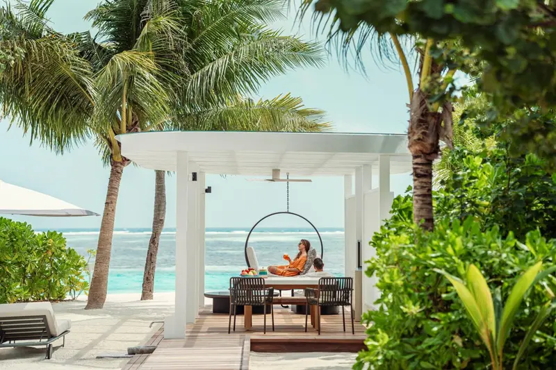 Une personne se détend sur une terrasse en bois avec vue sur la mer.
