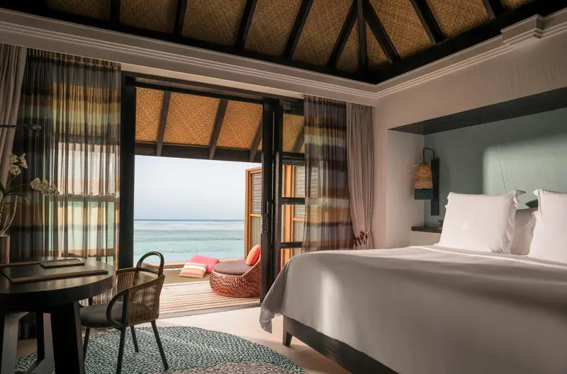 Une chambre lumineuse s'ouvre sur une terrasse avec vue sur la mer.