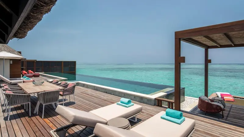 Terrasse en bois avec mobilier de détente et piscine à débordement donnant sur l'océan.