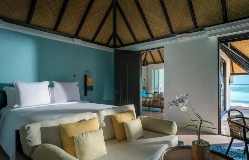 Une chambre lumineuse avec un lit et un coin salon.