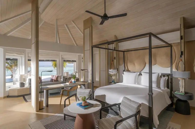 Une chambre lumineuse avec un grand lit à baldaquin et un coin salon.