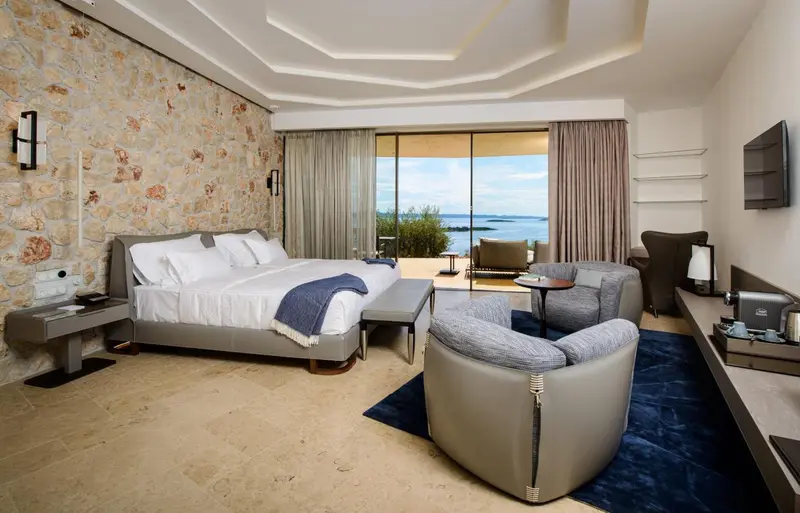 Une chambre spacieuse avec un grand lit et un coin salon donnant sur la mer.