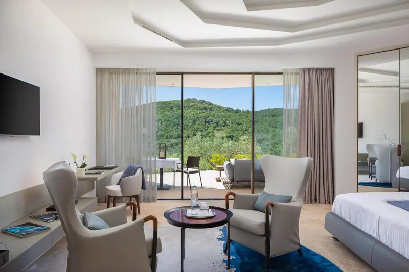 Une chambre lumineuse avec un coin salon et une vue sur la végétation.