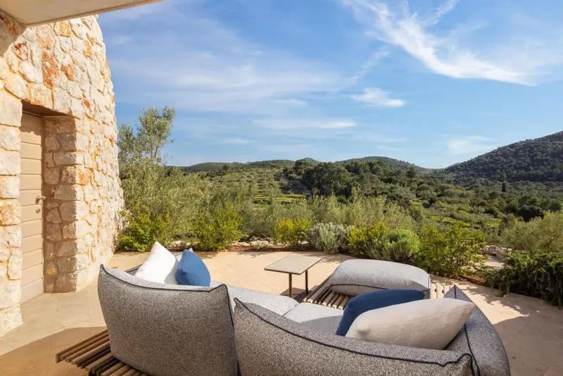 Espace de détente extérieur avec mobilier confortable et vue sur un paysage vallonné.