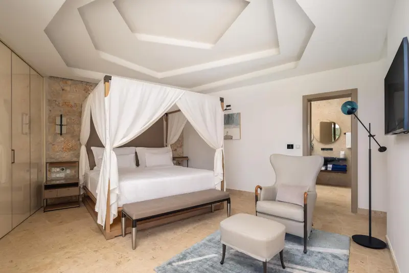 Une chambre lumineuse avec un grand lit à baldaquin et un fauteuil.