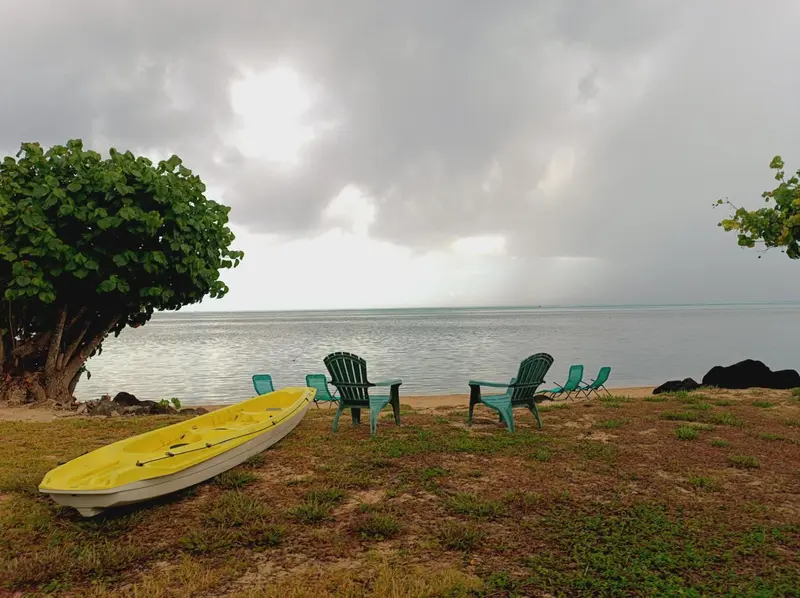 Chaise longue verte et kayak jaune sur une pelouse face à la mer.
