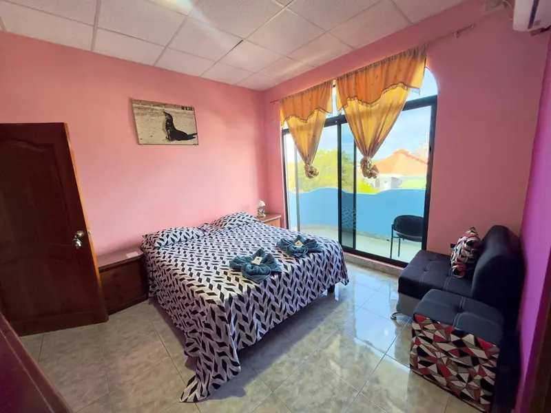 Une chambre lumineuse avec un lit recouvert d'une couverture à motifs et un coin salon.