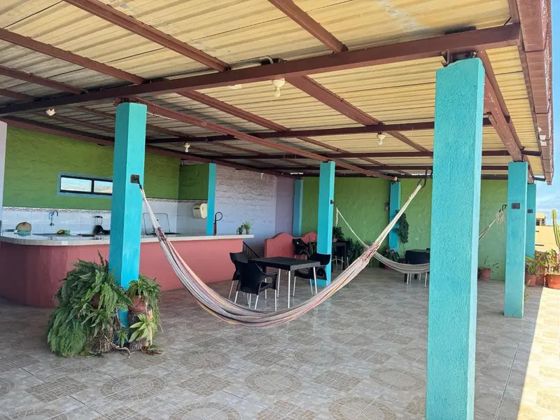 Espace de détente extérieur avec hamac et mobilier de jardin sous une pergola.
