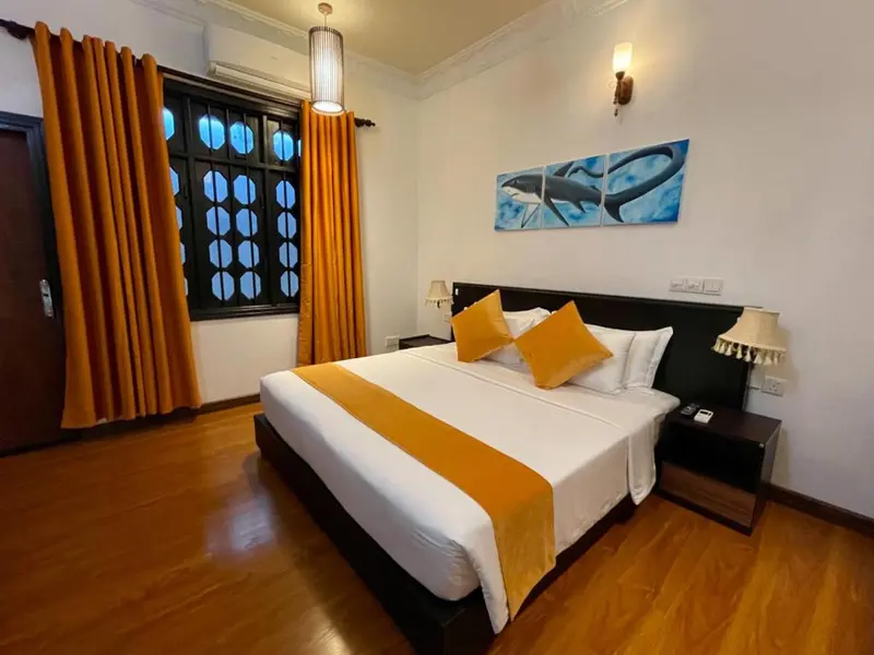 Une chambre lumineuse avec un grand lit recouvert d'une courtepointe orange.