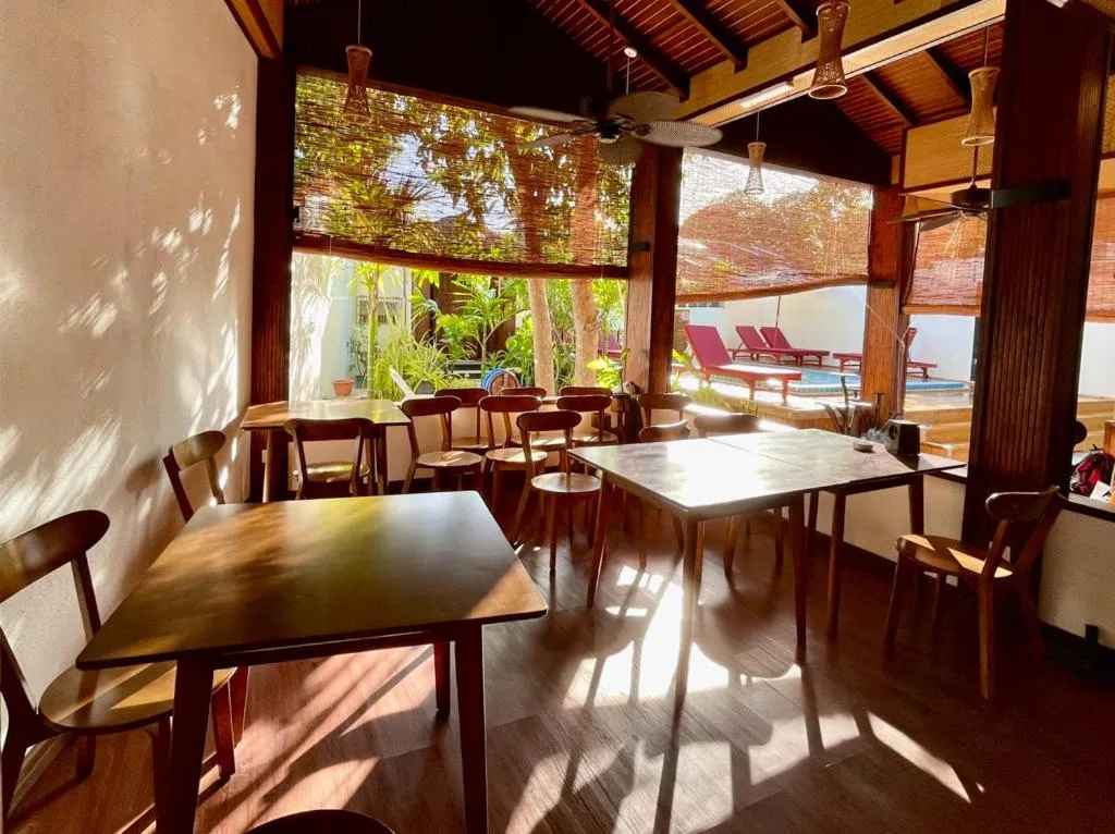 Une salle à manger lumineuse avec des tables en bois et des chaises.