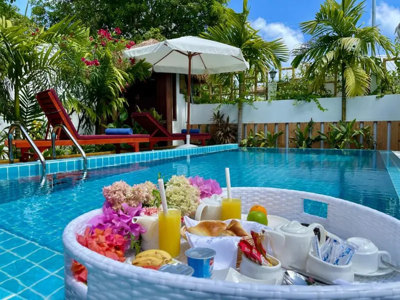 Un petit-déjeuner est servi sur un plateau flottant dans une piscine turquoise.