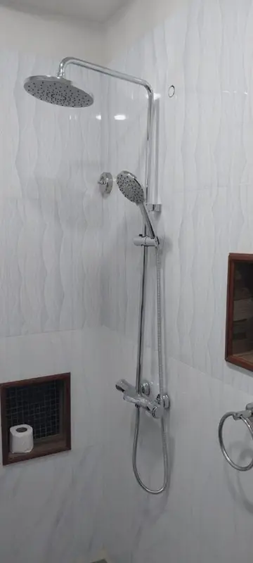 Une douche à l'italienne moderne avec des carreaux blancs texturés.