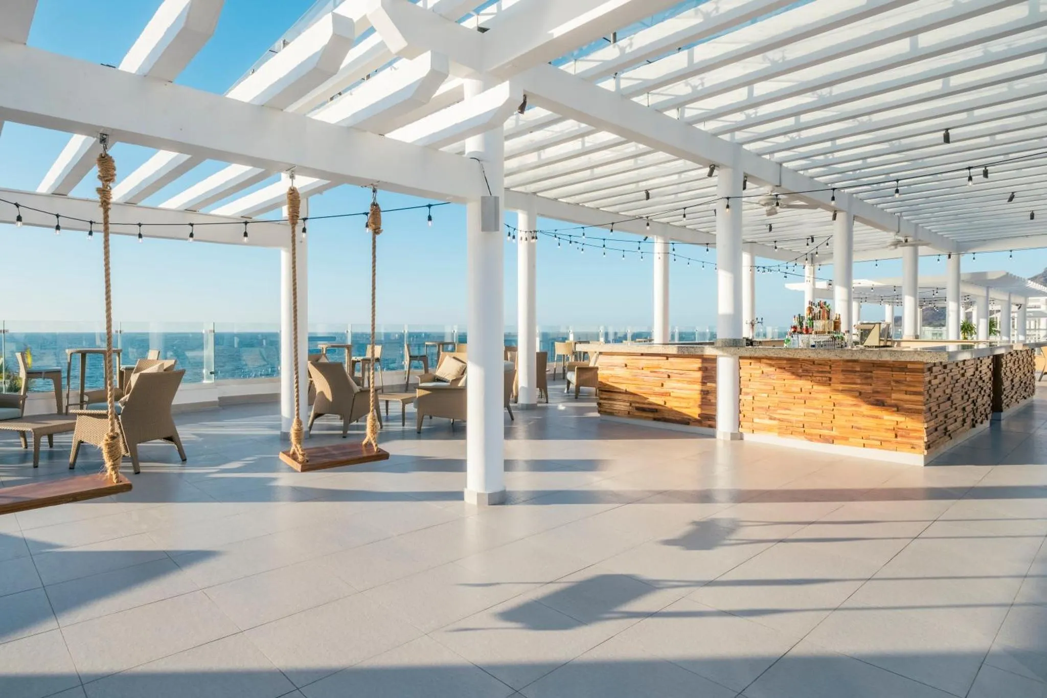 Terrasse ombragée avec bar et mobilier d'extérieur face à la mer.